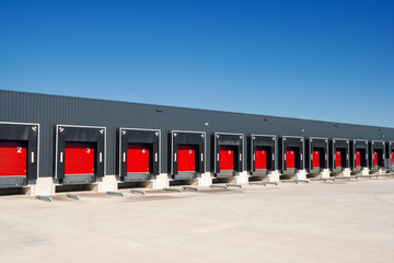 Row of loading docks with shutter doors at a warehouse - obrazy, fototapety, plakaty