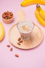 Fresh made banana smoothie in a glass on pink background