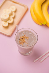 Fresh made banana smoothie in a glass on pink background