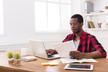 Black businessman in casual office, work with laptop and documents