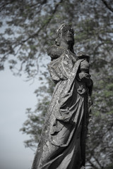 A stone statue was demolished on a grave in an old cemetery.