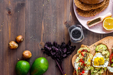Vegetarian breakfast. Sandwiches with avocado, fried eggs and paprika on wooden table top view copyspace