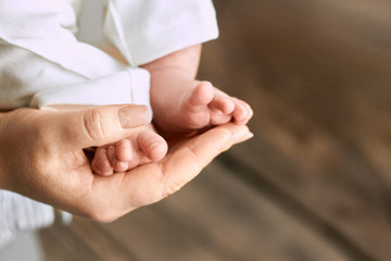 Female hand holding baby feet. Legs of child close up. Life and motherhood.