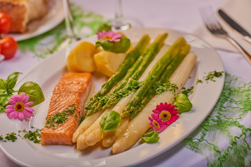 Seelachsfilet mit grünem und weißen Spargel und essbare Blumen serviert
