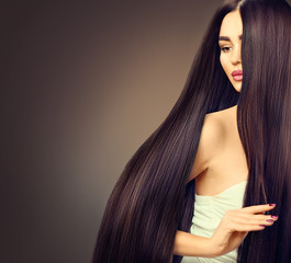 Beautiful brunette model girl with long straight black hair over dark background