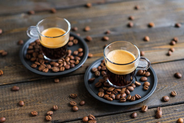 Two cups of espresso and coffee beans on a wooden table
