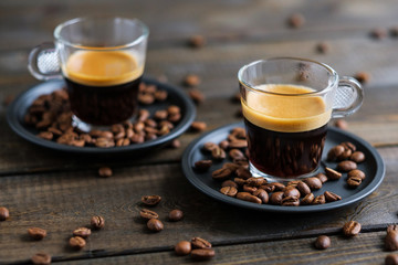 Two cups of espresso and coffee beans on a wooden table