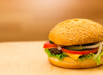 Burger close-up on a board. A burger with a meatball and fresh vegetables.