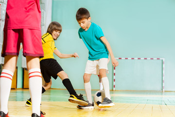 Happy boys playing football in school sports hall