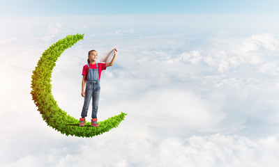 Concept of careless happy childhood with girl on green moon