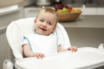 Little boy sitting in a high chair and laughing
