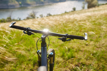 Fototapeta na wymiar Close-up of the handlaber of mountain bicycle against beautiful landscape in summer season.
