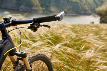 Fototapeta na wymiar Close-up of the handlaber of mountain bicycle against beautiful landscape in summer season.