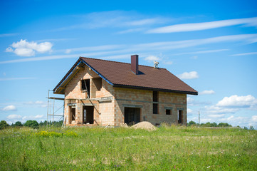 Brick House construction site. Building construction ceramic brick house. Unfinished Home Construction with roof.