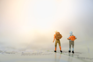 Travelling concepts. Two of traveler miniature people mini figures with backpack standing on map