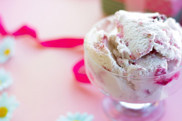 berry ice cream in glass dessert bowl on blurred background with gifts, sweets, pink background, selective focus, blur