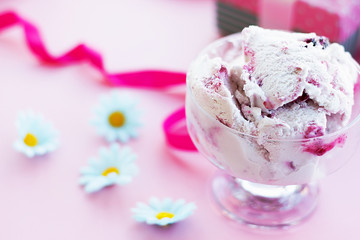 berry ice cream in glass dessert bowl on blurred background with gifts, sweets, pink background, selective focus, blur