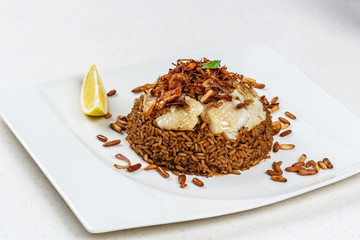 Traditional Middle Eastern fish and fried rice dish with fried pine nuts