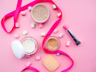 Fototapeta premium Fashion concept : Flat lay of pink cute woman bag lipstick, creams, honey, marshmallow, powder on colorful background with copy space