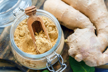 Wooden scoop and ground ginger in a glass jar.