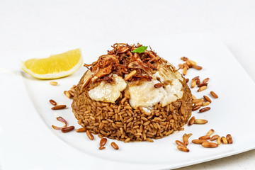 Traditional Middle Eastern fish and fried rice dish with fried pine nuts