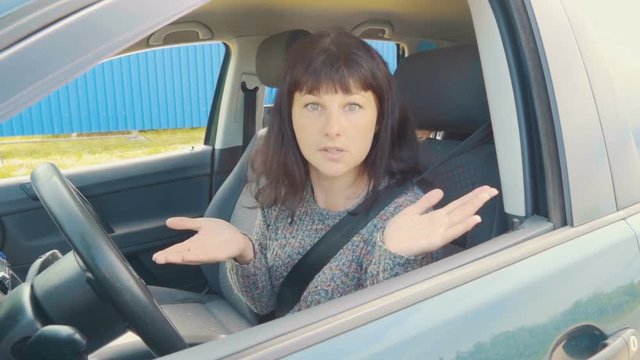 Young angry woman in perplexity sitting in the car.