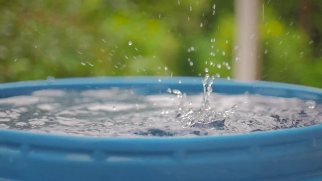 Drops of water from the roof fall into a blue barrel