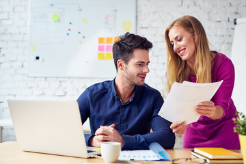 Attractive young businesswoman discussing documents and flirting with work colleague