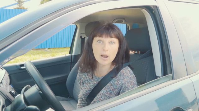Young angry woman in perplexity sitting in the car.Slow Motion.