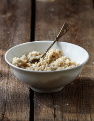 Ready-made, hot oatmeal in a white plate with a spoon