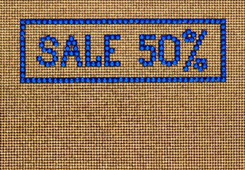 Word SALE is made rhinestones blue color on a gold canvas background.