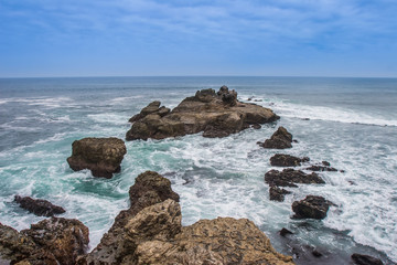 Fototapeta na wymiar Cliffs in the ocean. Waves breaking on the rocks. Pacific Ocean.