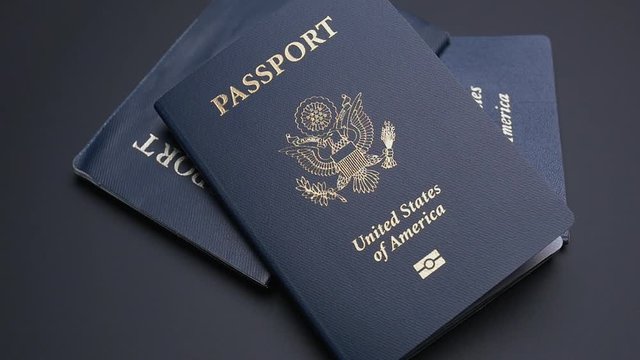 THREE AMERICAN PASSPORTS DROP INTO FRAME IN SLOW MOTION
