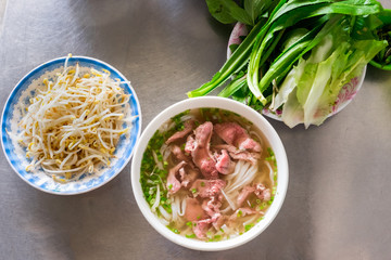 A traditional Vietnamese soup Pho Bo, with raw beef, green onions, soy sprouts