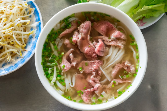 A traditional Vietnamese soup Pho Bo, with raw beef, green onions, soy sprouts