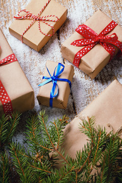 Different New Year's gifts wrapped in wrapping paper under the Christmas tree branch