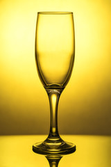 Empty wine glass with reflection, on the skylight, on a yellow background with a gradient spot