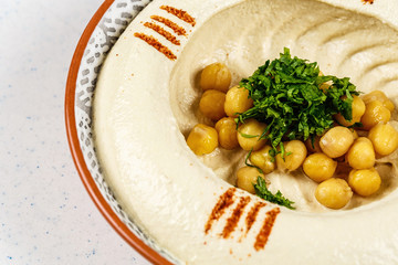 Arabic food Hummus with parsley in a traditional bowl.