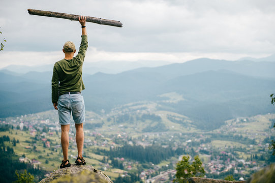 Strong man with wooden staff stick looking far at horizon. Primal leader. Masculine power. Discover, coquer. Kingdom lord. Edge of world. Nature spirit salutation. Rude strength. Reaching highest peak