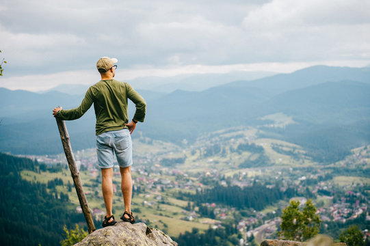 Strong man with wooden staff stick looking far at horizon. Primal leader. Masculine power. Discover, coquer. Kingdom lord. Edge of world. Nature spirit salutation. Rude strength. Reaching highest peak