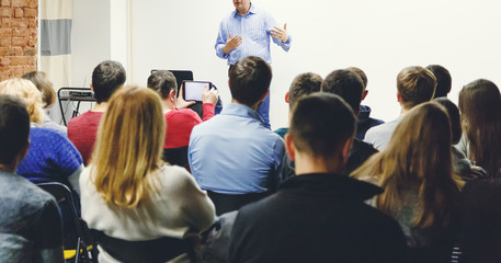 Adult students listen to professor's lecture in small class room. Panoramic aspect ratio. - obrazy, fototapety, plakaty