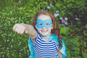 Laughing superhero girl in summer park.