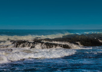 Waves breaking at rocks of the Indian Ocean at the Wild Coast of South Africa with cloudy sky