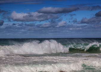 Breaking waves of the Indian Ocean at the Wild Coast of South Africa with cloudy sky