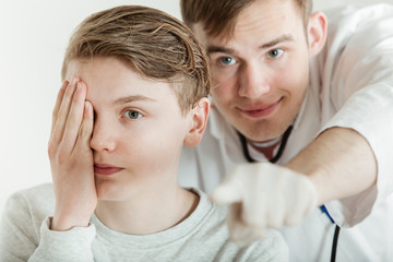 Doctor Standing Behind Teen Boy During Vision Test