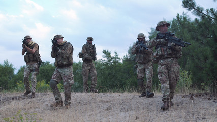 Group of soldiers in a camouflage and with weapon carry out investigation of the territory
