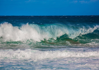 Breaking waves of the Indian Ocean at the Wild Coast of South Africa with cloudy sky