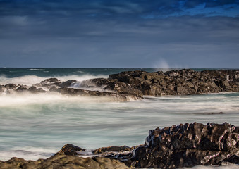 Waves breaking at rocks of the Indian Ocean at the Wild Coast of South Africa with cloudy sky