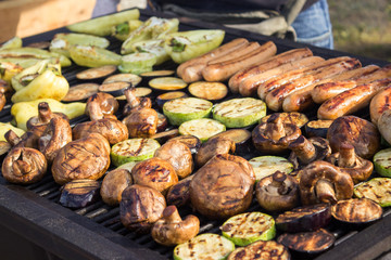 Assorted delicious grilled meats with vegetables over the barbecue on the charcoal. Sausages, steak, pepper, mushrooms, zucchini.