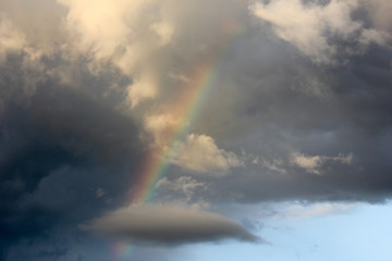 Naklejka na ściany i meble Evening sky after rain, rainbow leaves in a cloud shaped like a whale. Fabulously beautiful sky. Rainbow in the sky..
